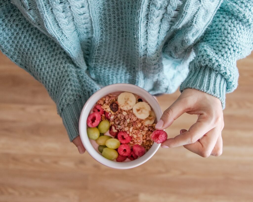 person holding white ceramic bowl with red and yellow beans